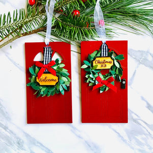 Wooden Red Doors with wreath and door plaque saying Christmas 2021 and Welcome. Both are Christmas Tree Ornaments